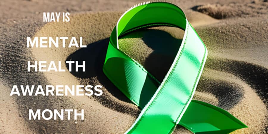 Green mental health awareness ribbon on the sand
