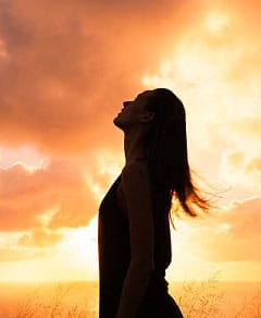 Silhouette of a woman in front of the sky at sunrise