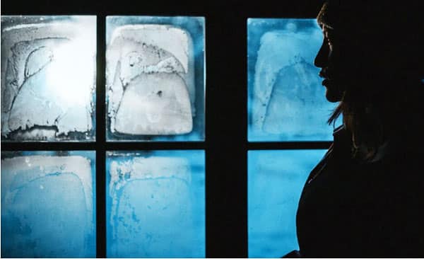 Silhouette of a person in front of blue windows